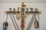 <center>Ancien évêché</center>Immédiatement après le regidor rouge, s’avance, encadrée par deux caparutxes noirs, la Croix des Outrages ( Creu dels Improperis). Cette croix de procession de bois polychrome représente sous la forme traditionnelle populaire et imagée, les seize groupes d’objets symbolisant les souffrances infligées au Christ et détaillées dans les Évangiles, depuis la trahison de la Cène jusqu’au coup de lance du légionnaire. Ce type de croix est souvent exposé dans les chapelles consacrées à la Passion.