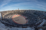 Les Arènes. <br> La cavea, entourant la piste, divisée en 60 travées rayonnantes et 34 rangs de gradins, pouvait accueillir 24 000 spectateurs. Les 34 rangs de gradins de la cavea sont répartis en quatre maeniana horizontaux, séparées par un couloir de circulation et un muret, appelé balteus.
Chaque maenianum était réservé à une classe sociale de la société nîmoise, à savoir les plus aisés aux premiers rangs et les plus modestes aux derniers rangs, et chacun desservi par une galerie voûtée, appelé vomitorium.